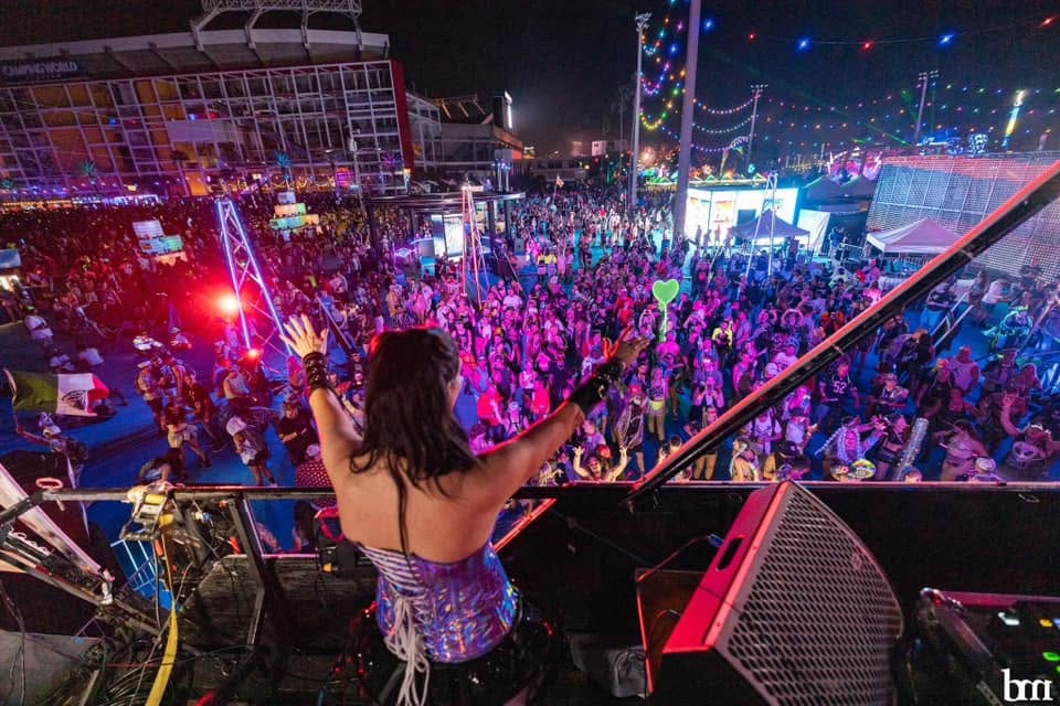 View from the stage over an outdoor crowd illuminated by colorful event lighting