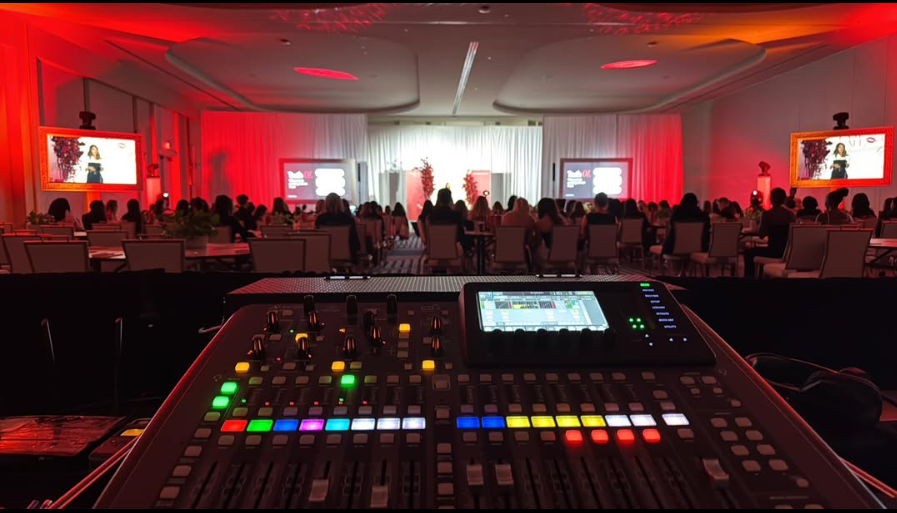 Audio mixing console overlooking a ballroom event with red lighting